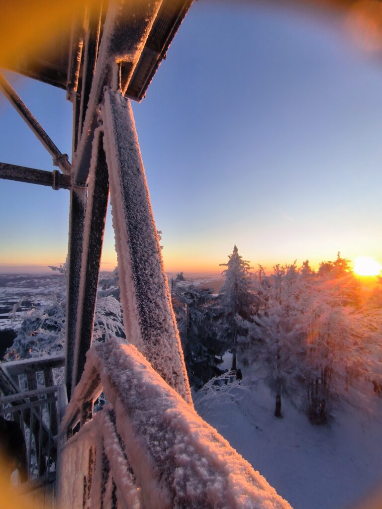 Zbliżenie na oblodzone barierki konstrukcji, jaką jest wieża widokowa na Mogielicy, z której widać zimową panoramę szczytów Beskidu Wyspowego