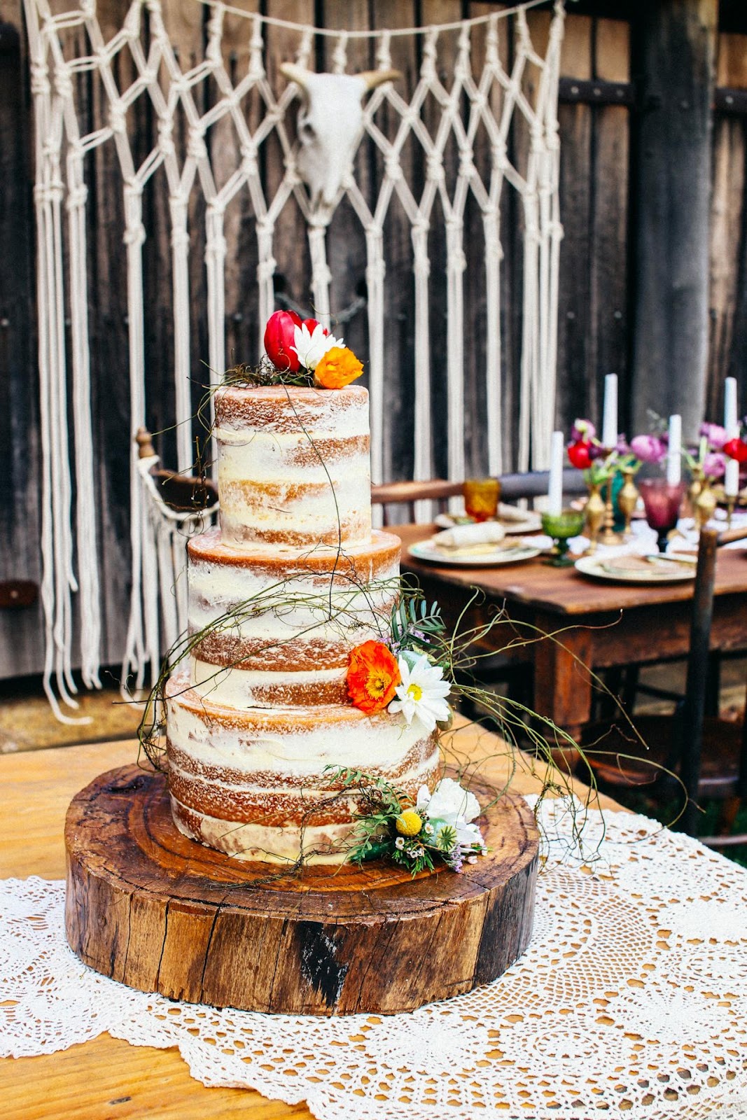 Tort weselny w rustykalnym stylu Elegancki rustykalny tort na wesele typu „naked cake" z kremem i kwiatami w otoczeniu słodkości.