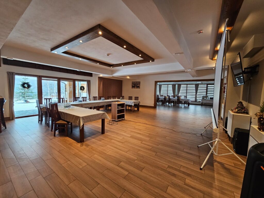 Nowoczesne wnętrze Serca Beskidu z dużym ekranem projekcyjnym i stołami ustawionymi w podkowę, przygotowane na efektywne jednodniowe szkolenie w okolicach Krakowa.